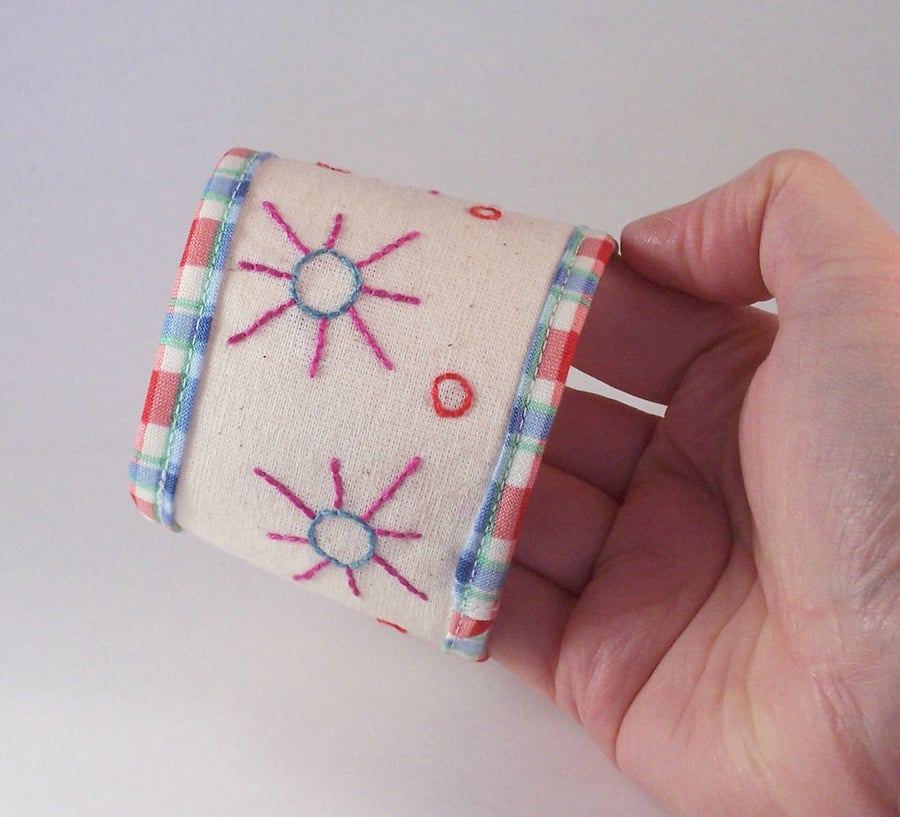 Textile cuff in cotton with button fastening and embroidered suns