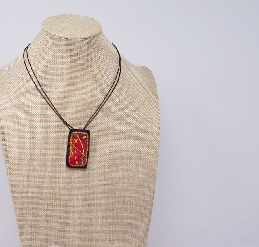 Embroidered silk textile necklace in fire colours.