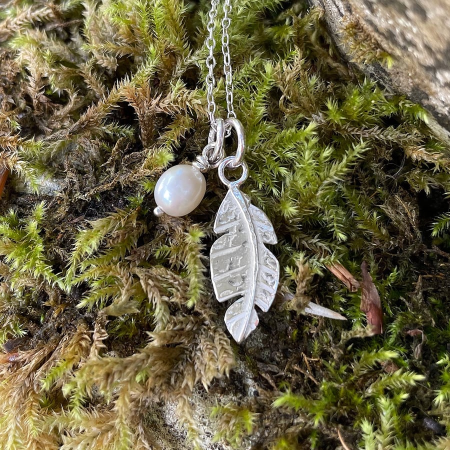 Silver feather and pearl charm pendants and chain necklace.