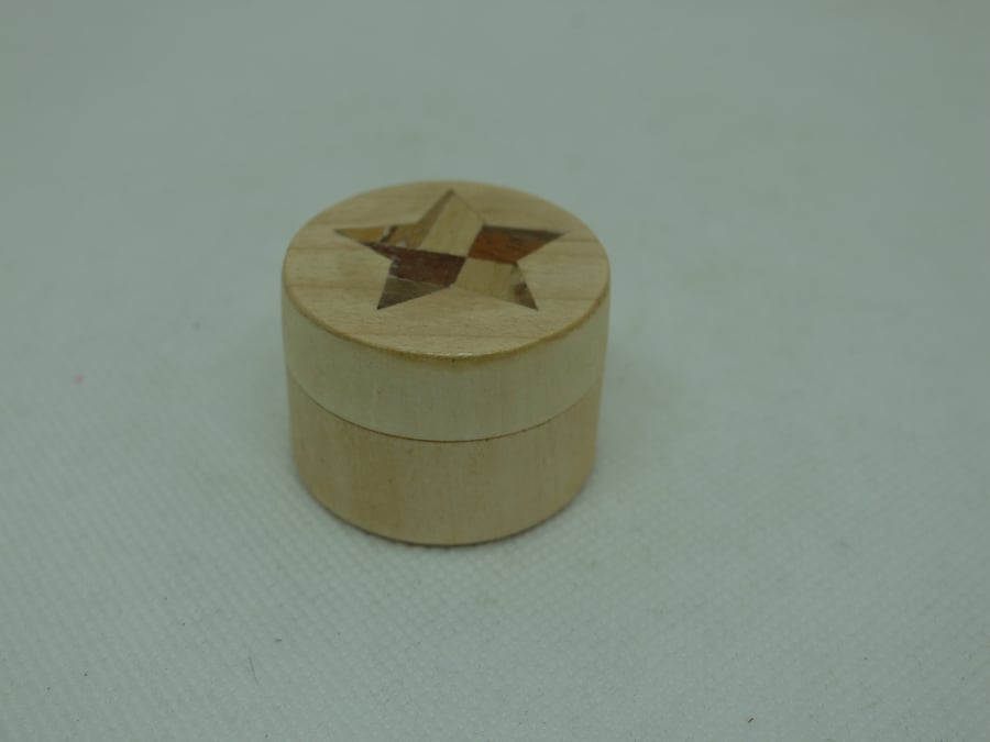 Tiny round wooden pot with star inset into light wood veneer on lid