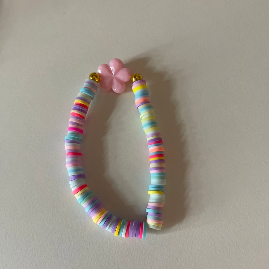 A clay bead bracelet with a flower charm and spring colours.