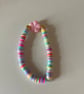 A clay bead bracelet with a flower charm and spring colours.