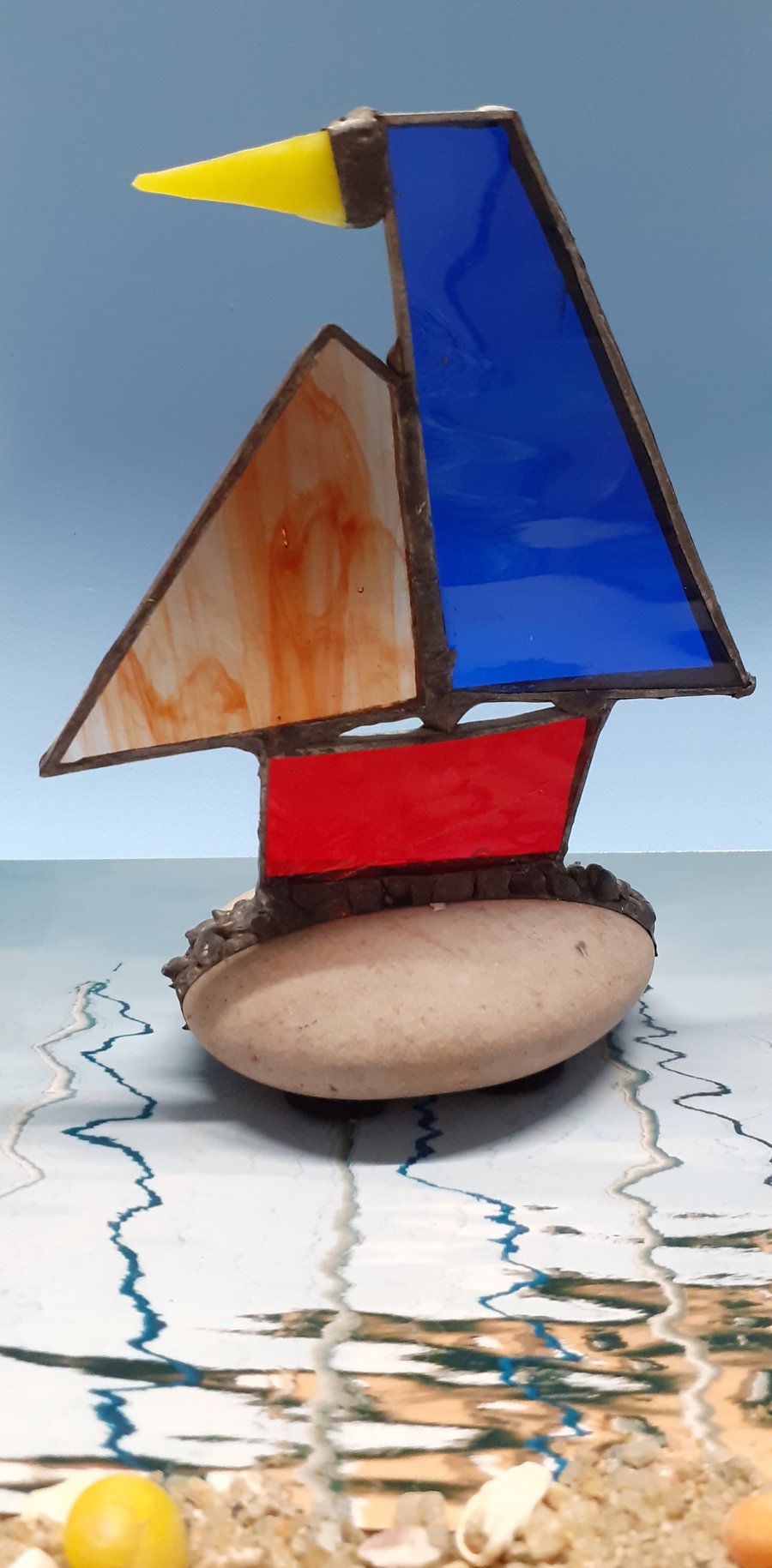 Stained glass sailing boat on pebble
