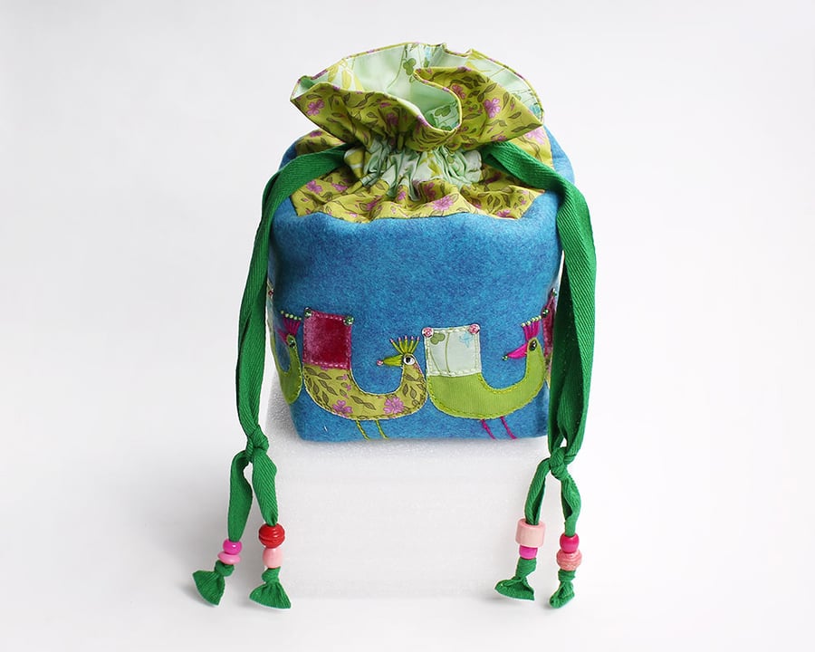 Turquoise wool felt drawstring bag with hand stitched peacocks all around