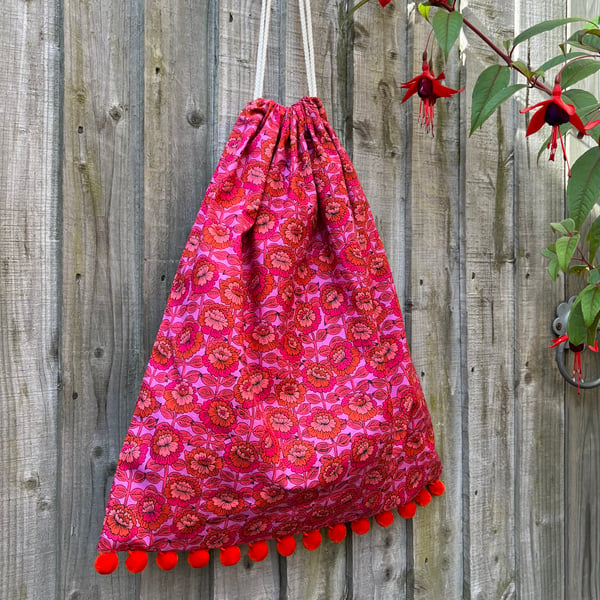 Bright pink, purple and orange floral cotton drawstring bag with pompoms unlined