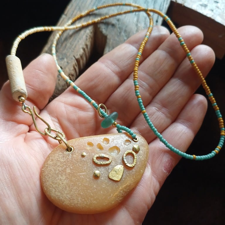 Abstract pebble pendant on glass bead necklace.