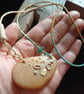 Abstract pebble pendant on glass bead necklace.