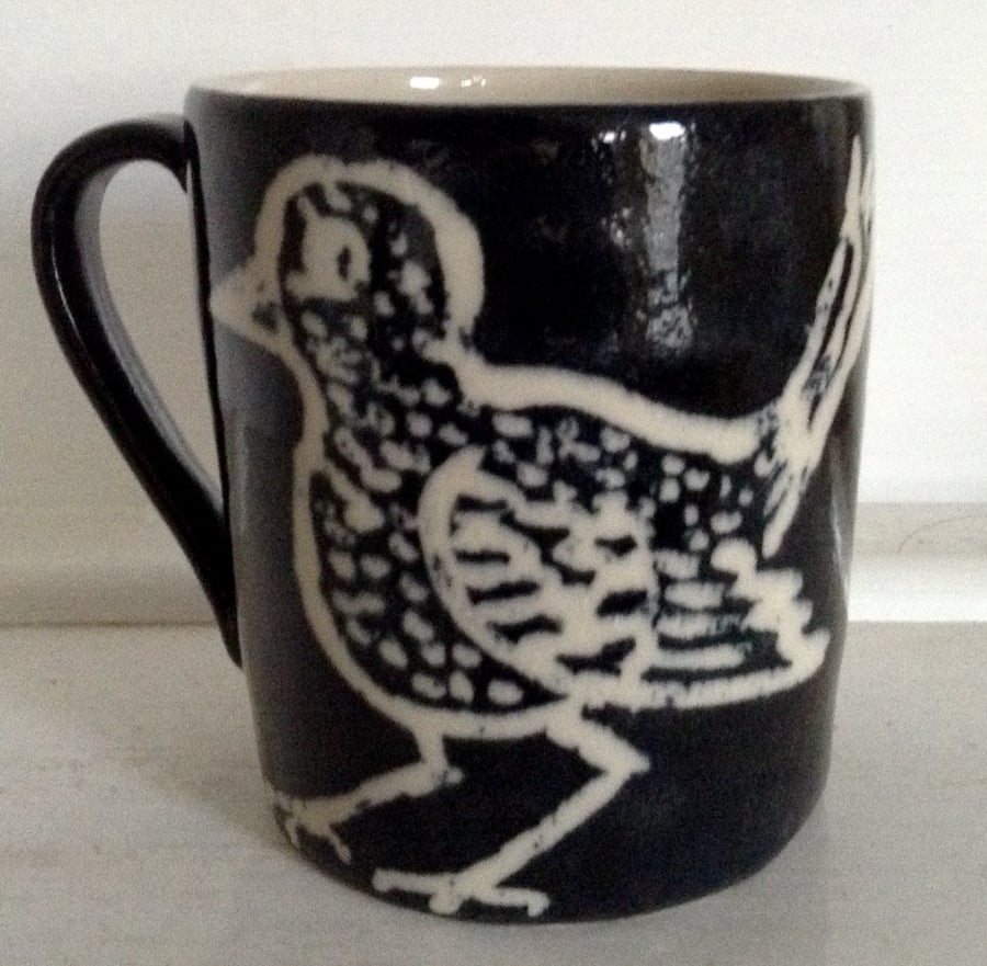 Mug in cream stoneware with black and cream bird decoration.     