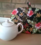Small Tea Cosy with Red Hibiscus Flowers on a Black Background