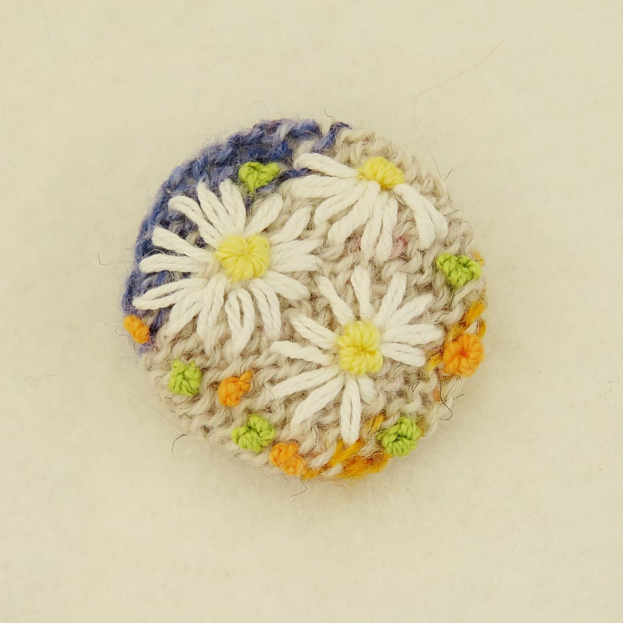 Daisy Brooch embroidered on knitted blue and cream background