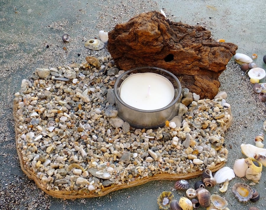 Pebble beach scene with glass tealight holder & tealight & driftwood backdrop.