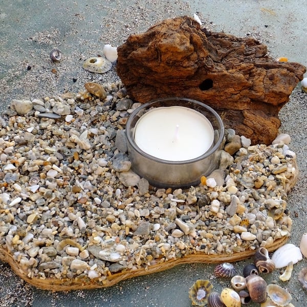 Pebble beach scene with glass tealight holder & tealight & driftwood backdrop.