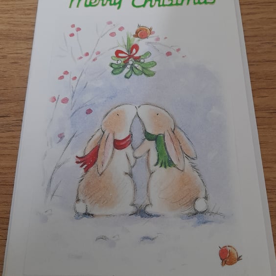 CUTE CHRISTMAS CARD WITH TWO RABBITS KISSING UNDER THE MISTLETOE.
