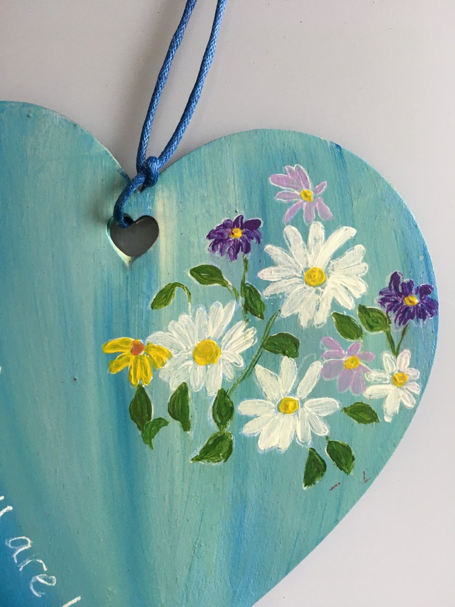 Hand painted wooden heart with flowers and text.