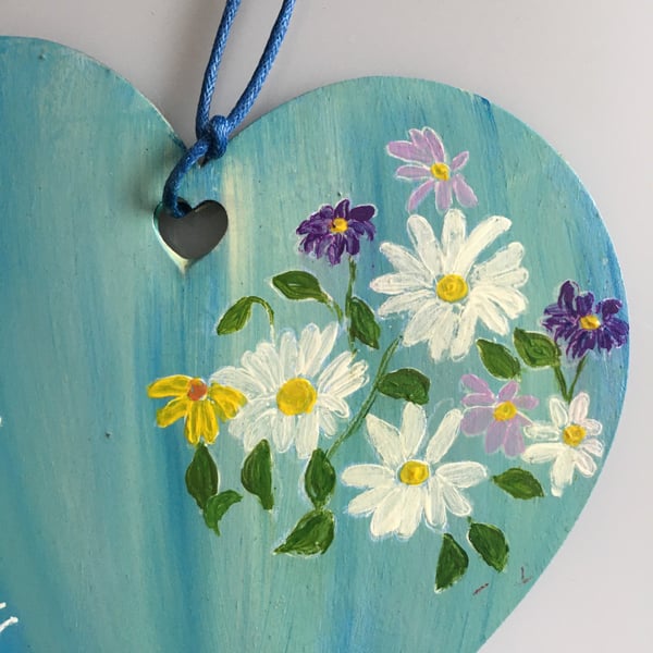 Hand painted wooden heart with flowers and text.