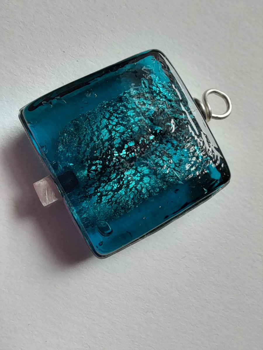 Deep turquoise glass pendant set in silver surround and drop. 
