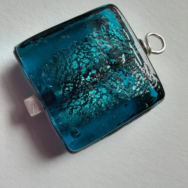 Deep turquoise glass pendant set in silver surround and drop. 