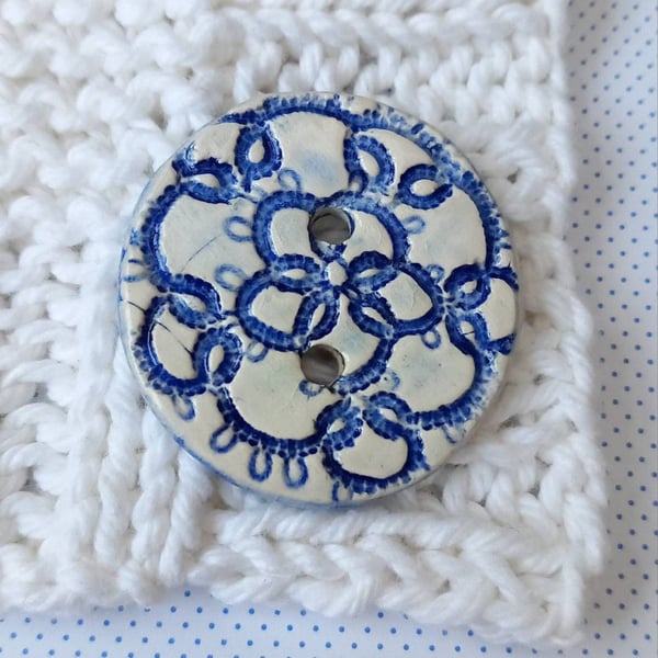 Big blue and white button embossed with a hand tatted lace motif. 