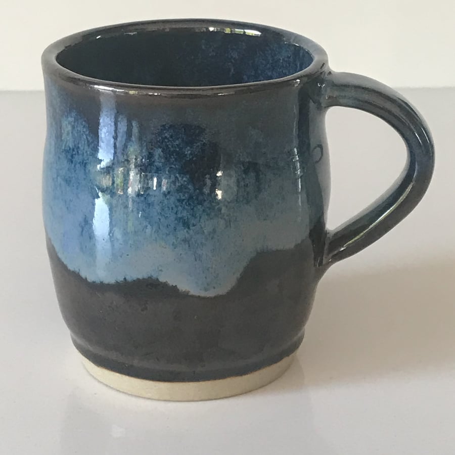 Stoneware pottery mug finished in blue and black glaze combination.