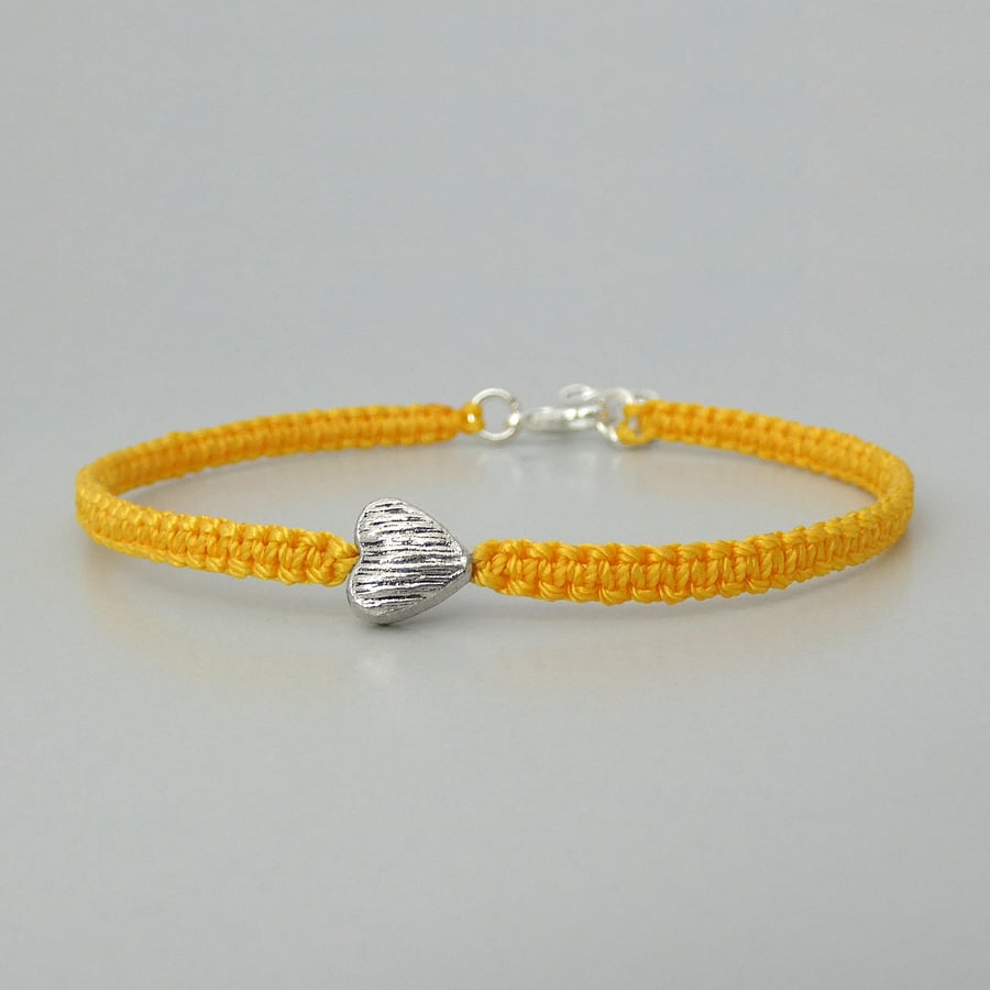 Yellow 7" macramé bracelet with silver plated heart charm and 1” extender chain.