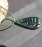 Metallic green and bronze fern tear-drop pendant on a green woven cord.