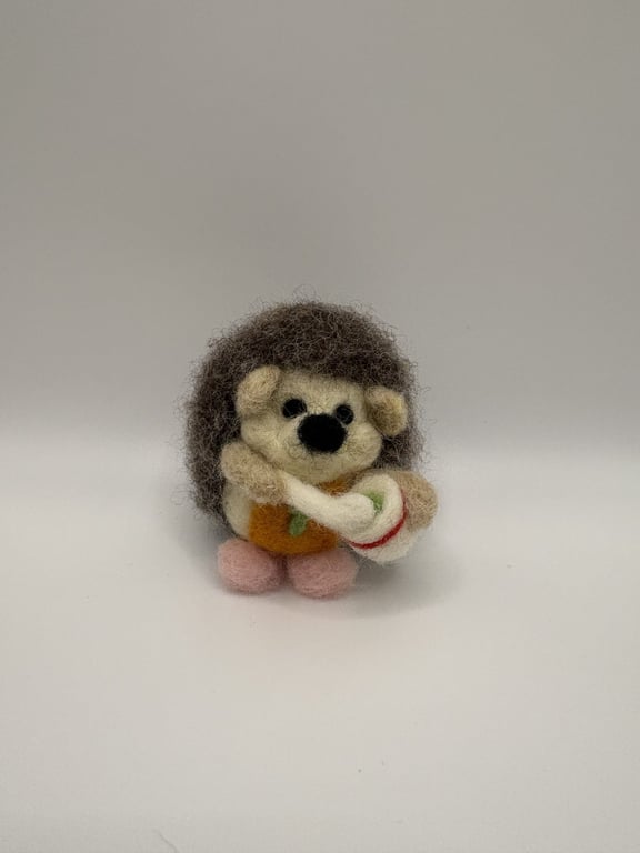 Handmade needle felted hedgehog baking a cake wearing an apron and pink slippers