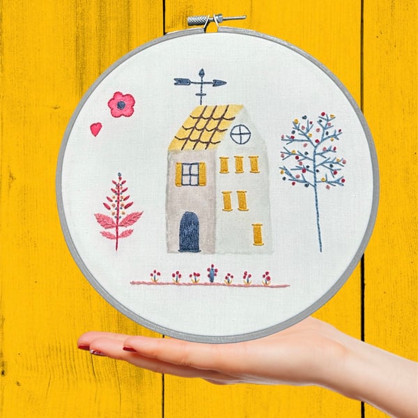 Embroidered hoops art of a Mediterranean house with weather vane and it’s garden