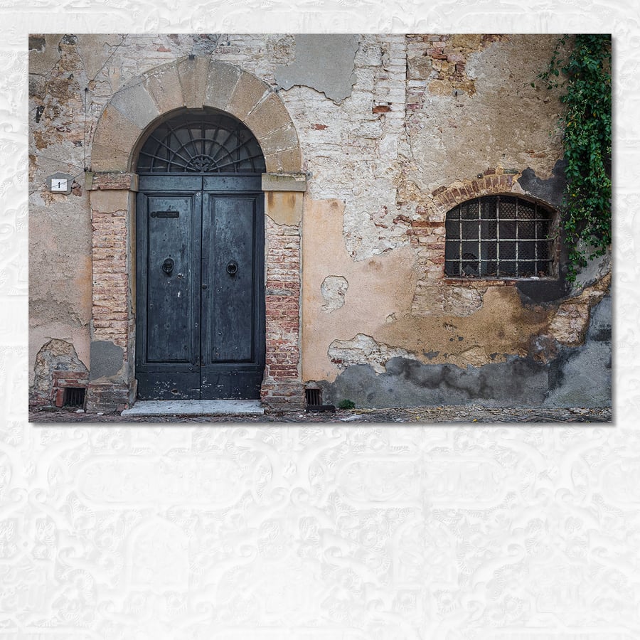 Aged door and barred window in a weathered brick building in Tuscany