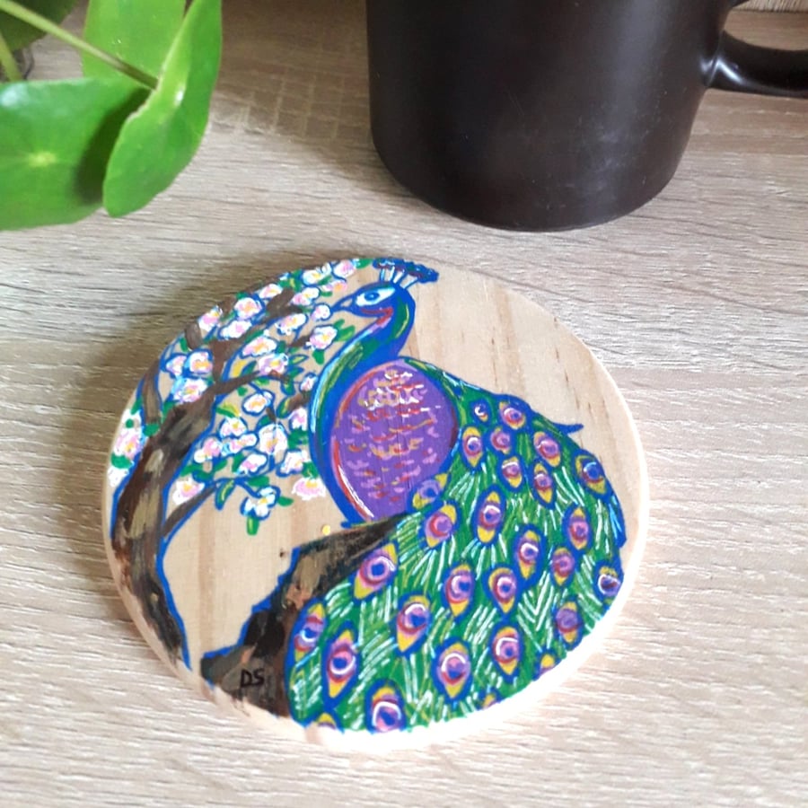 Wooden coaster handpainted with a colourful Peacock bird next to a cherry tree.