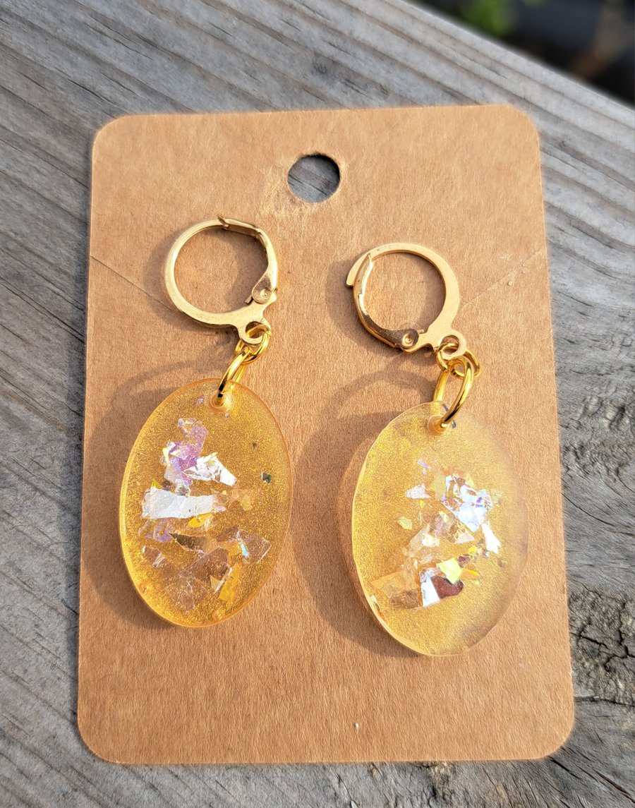 Oval resin earrings filled with gold and multicoloured glitter flakes