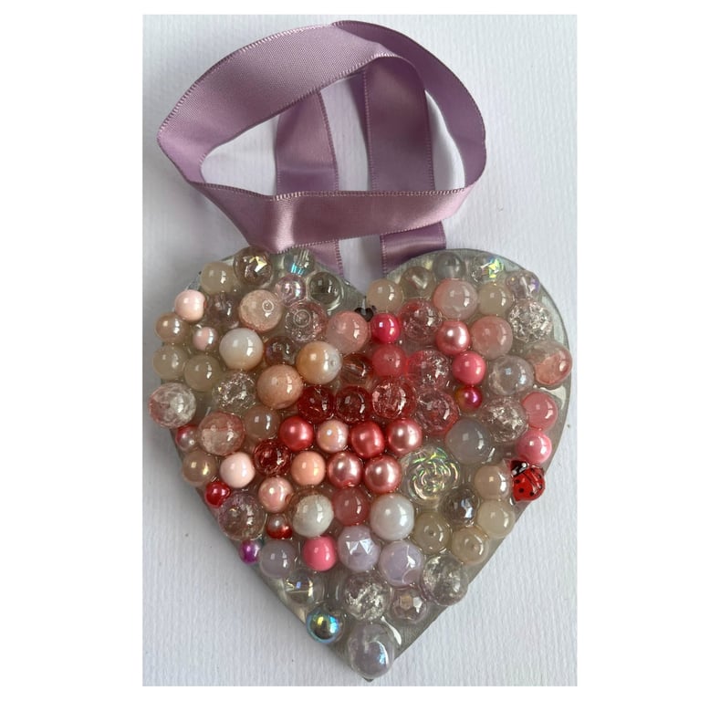 A wooden heart shaped pendant with pink and rose coloured spheres.