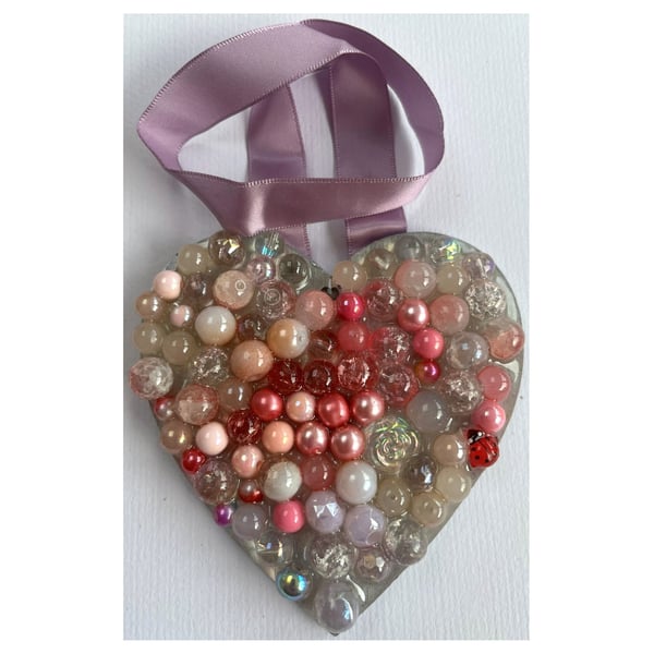 A wooden heart shaped pendant with pink and rose coloured spheres.
