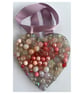 A wooden heart shaped pendant with pink and rose coloured spheres.