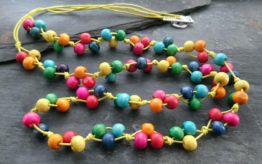 Rainbow coloured wooden bead necklace on yellow cotton cord