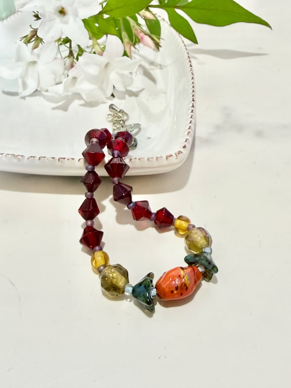 Slender glass bead bracelet in earthy shades of red and orange. 