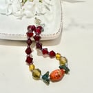 Slender glass bead bracelet in earthy shades of red and orange. 
