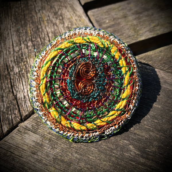 Flat disc brooch in yellow, copper, green made from recycled materials