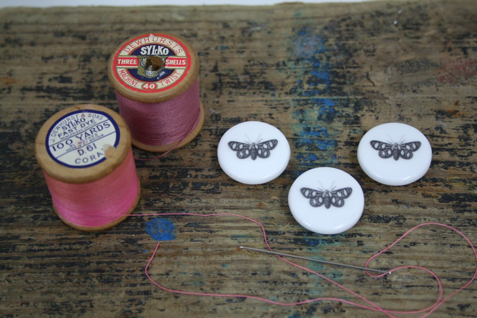 A set of three bone china buttons with moth image