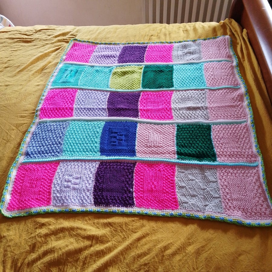 Handmade knitted baby or toddler blanket in a multi coloured theme