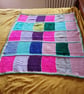 Handmade knitted baby or toddler blanket in a multi coloured theme