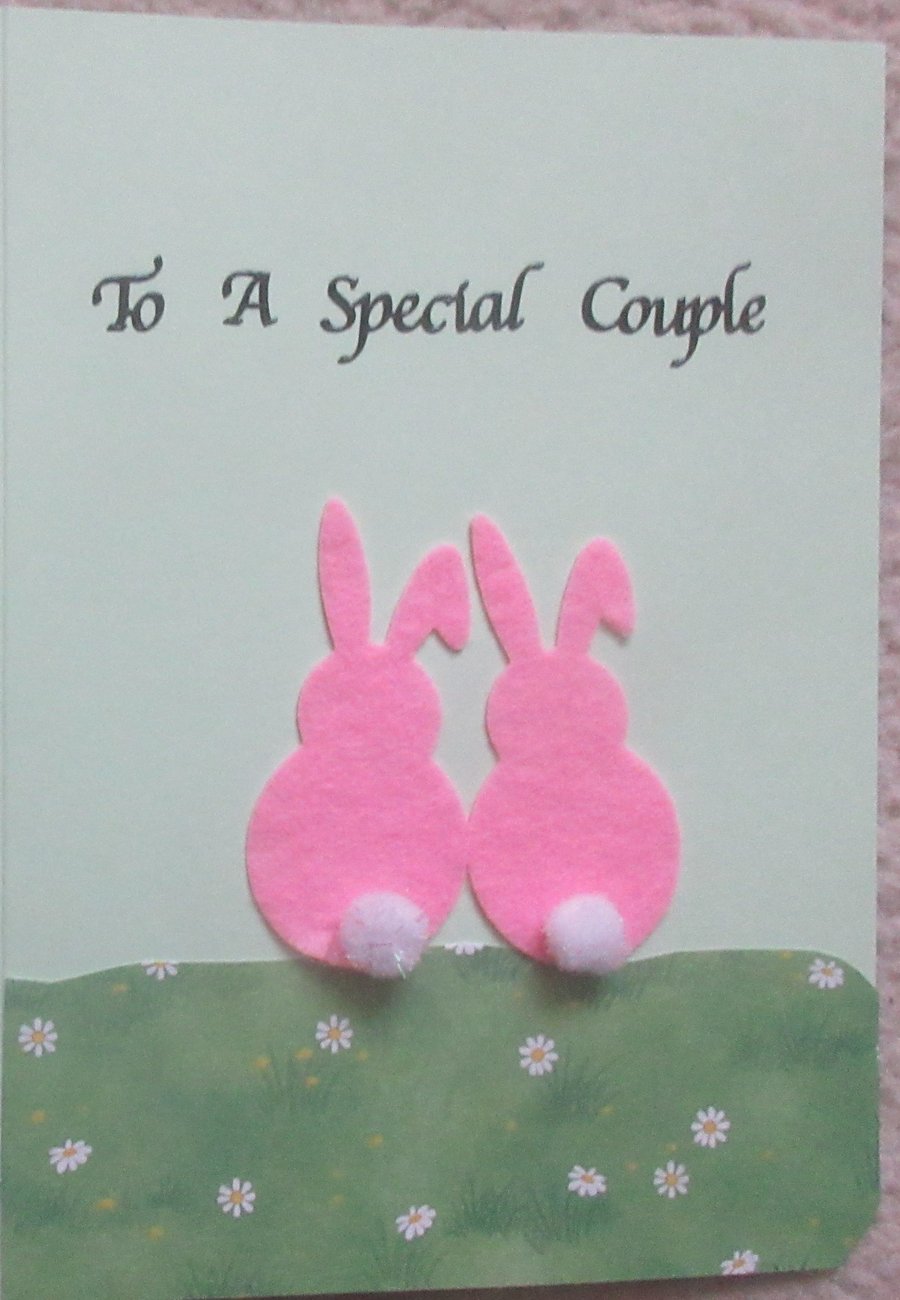 To a Special  Couple - Two pink felt bunnies sitting on a hill of daisies