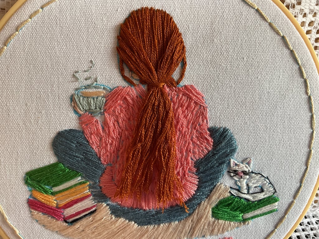 A  Girl sitting on the carpet next to a pile of books with her pet cat 