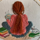 A  Girl sitting on the carpet next to a pile of books with her pet cat 