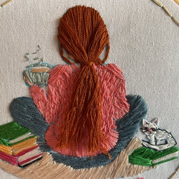 A  Girl sitting on the carpet next to a pile of books with her pet cat 