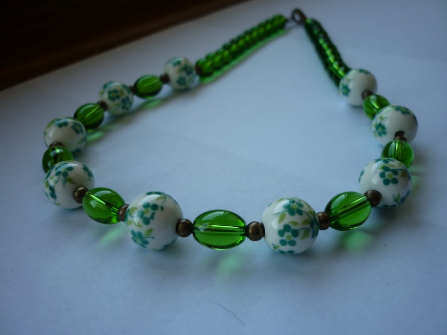 GREEN, WHITE AND ANTIQUE BRONZE PORCELAIN BEAD NECKLACE.