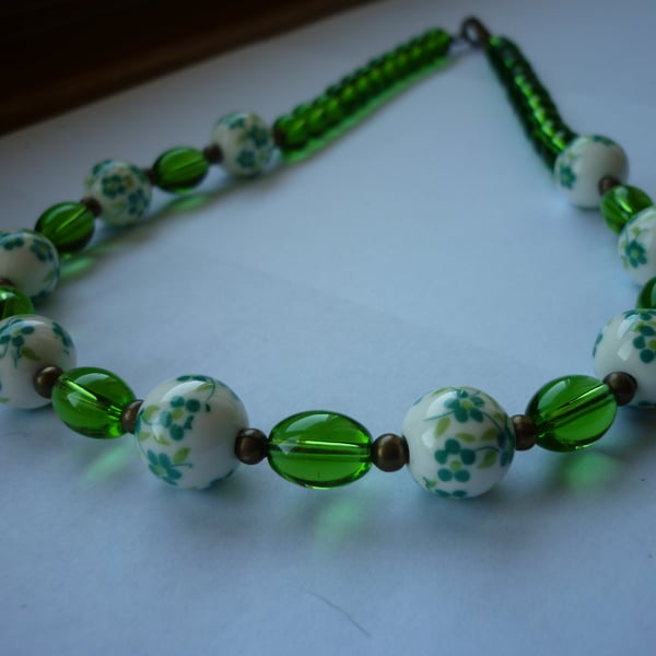 GREEN, WHITE AND ANTIQUE BRONZE PORCELAIN BEAD NECKLACE.