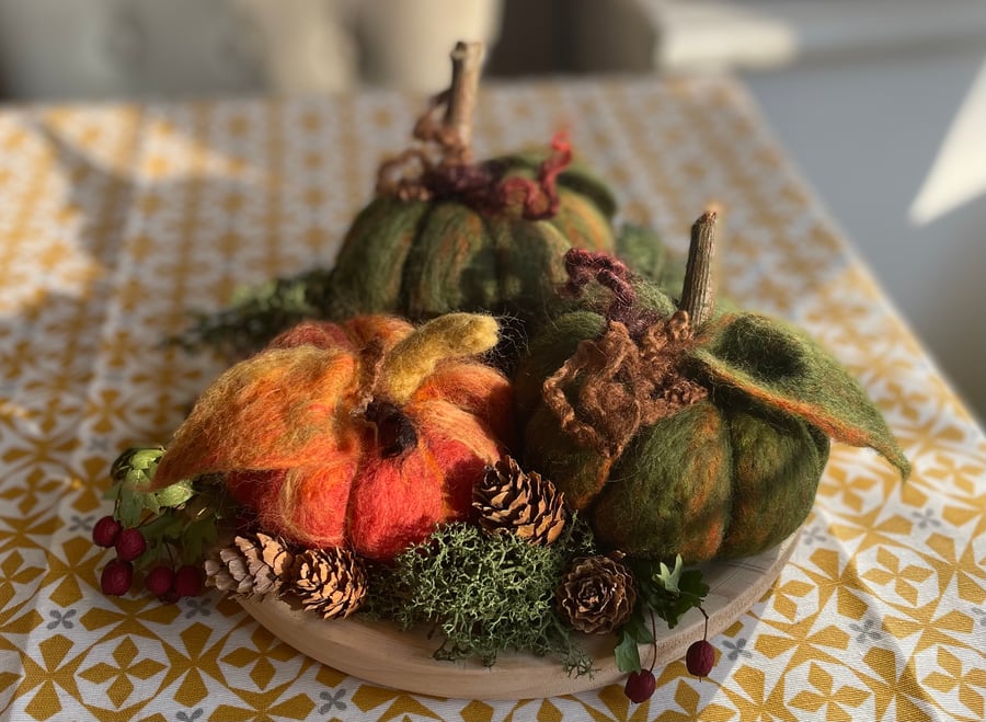 Felted green and orange 3 pumpkins on wooden plate with natural decoration