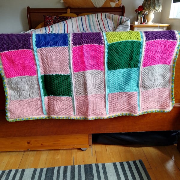 Handmade knitted baby or toddler blanket in a multi coloured theme
