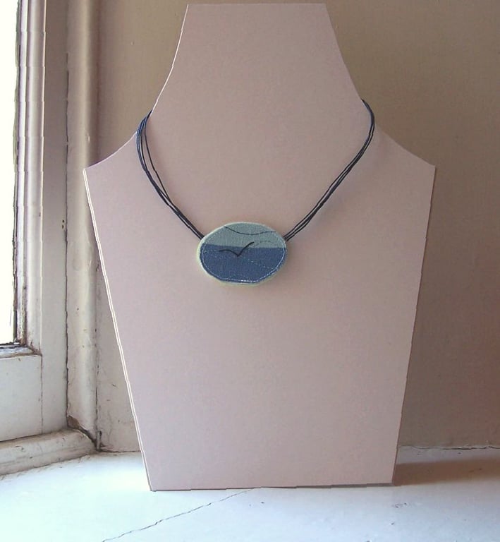 Oval hand and machine embroidered textile necklace with seabird silhouette