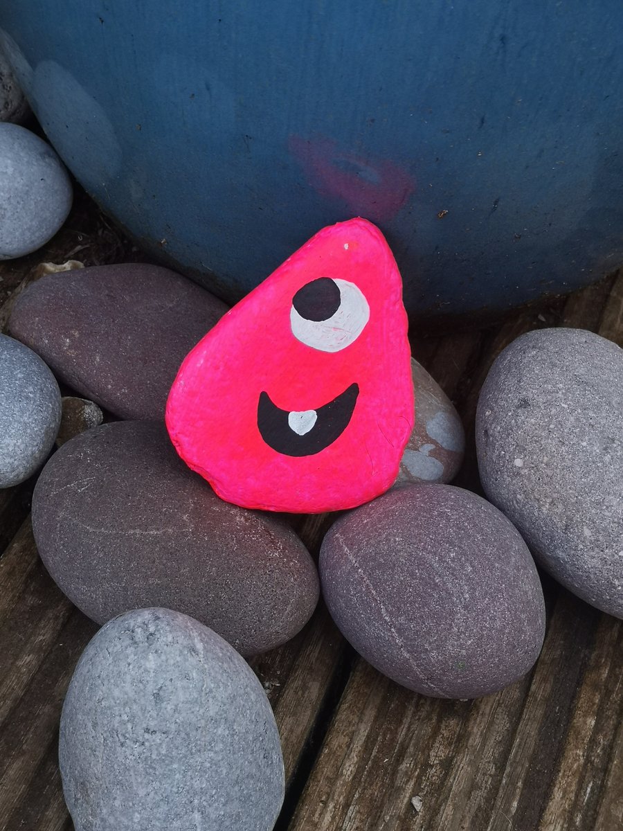Bright pink funny face painted rock pebble. 